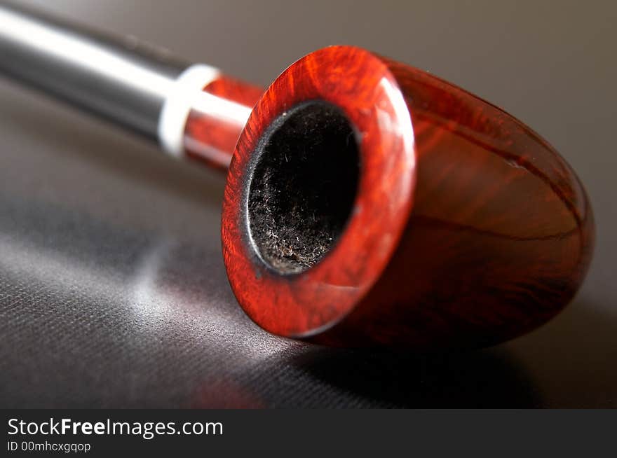 Red textured smoking pipe at black background