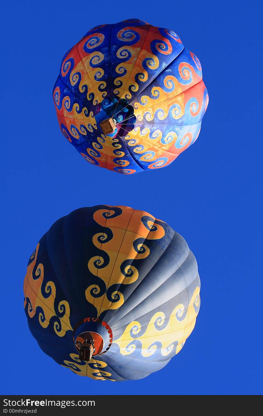 Two colorful hot air balloons in a blue sky