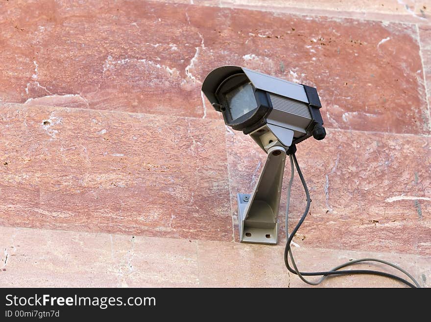 Security camera mounted on pink stone wall