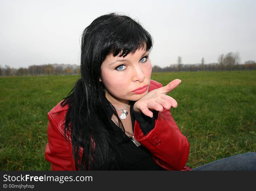 Woman show a kiss in park, sitting on grass