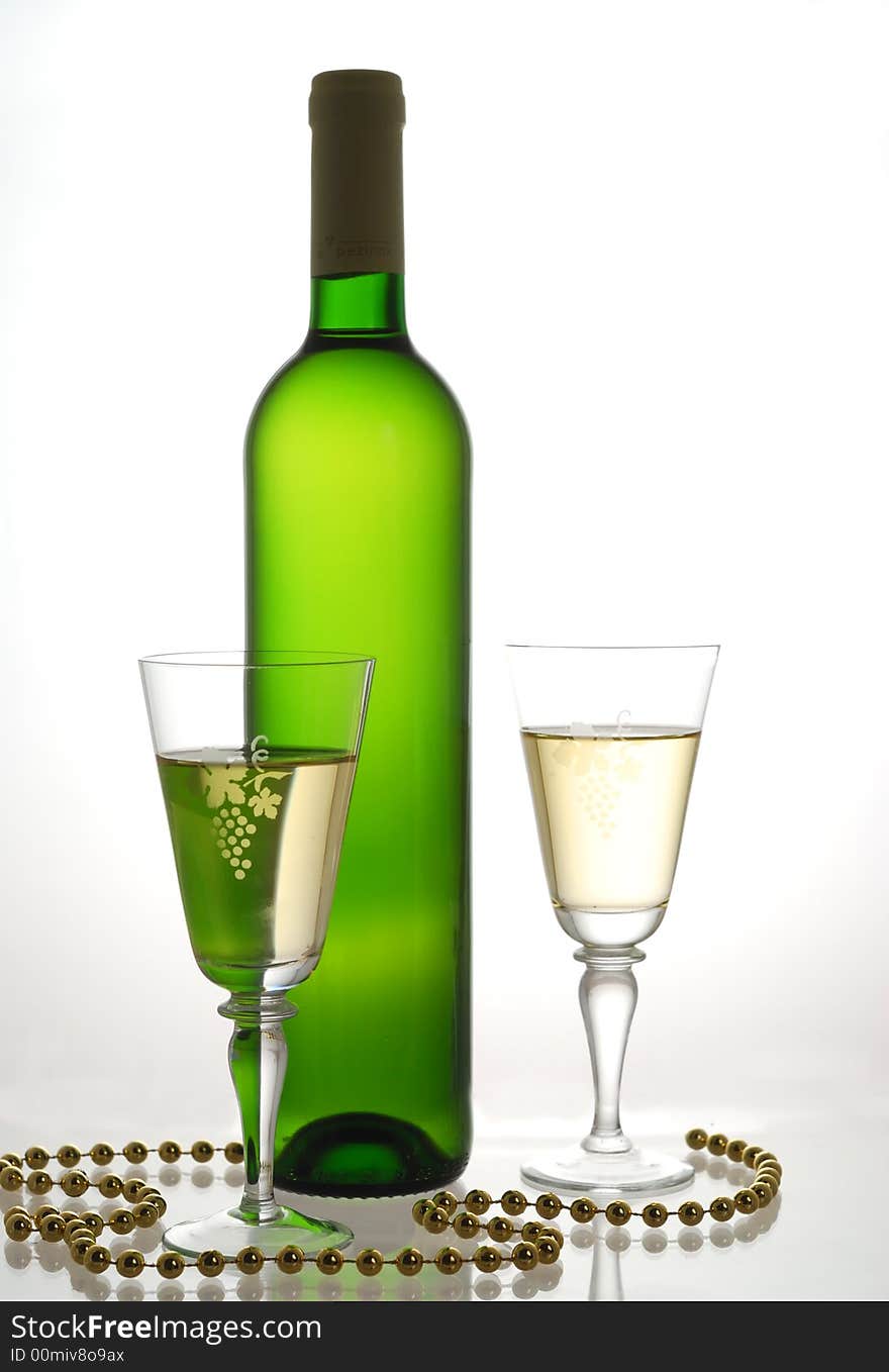 Bottle and glasses of white wine opposite white light