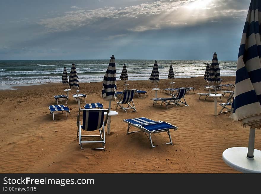 Beach with deckchairs, umbrellas and dramatic sky. Beach with deckchairs, umbrellas and dramatic sky