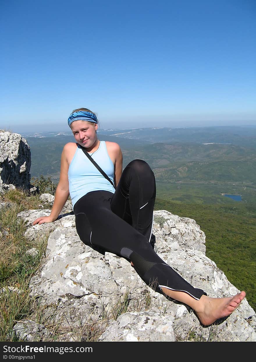 Sporty girl sitting above the mountain background. Sporty girl sitting above the mountain background