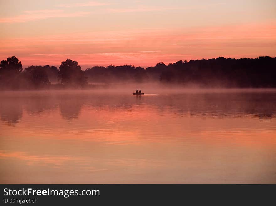 Morning angler on the lake in red sunshine