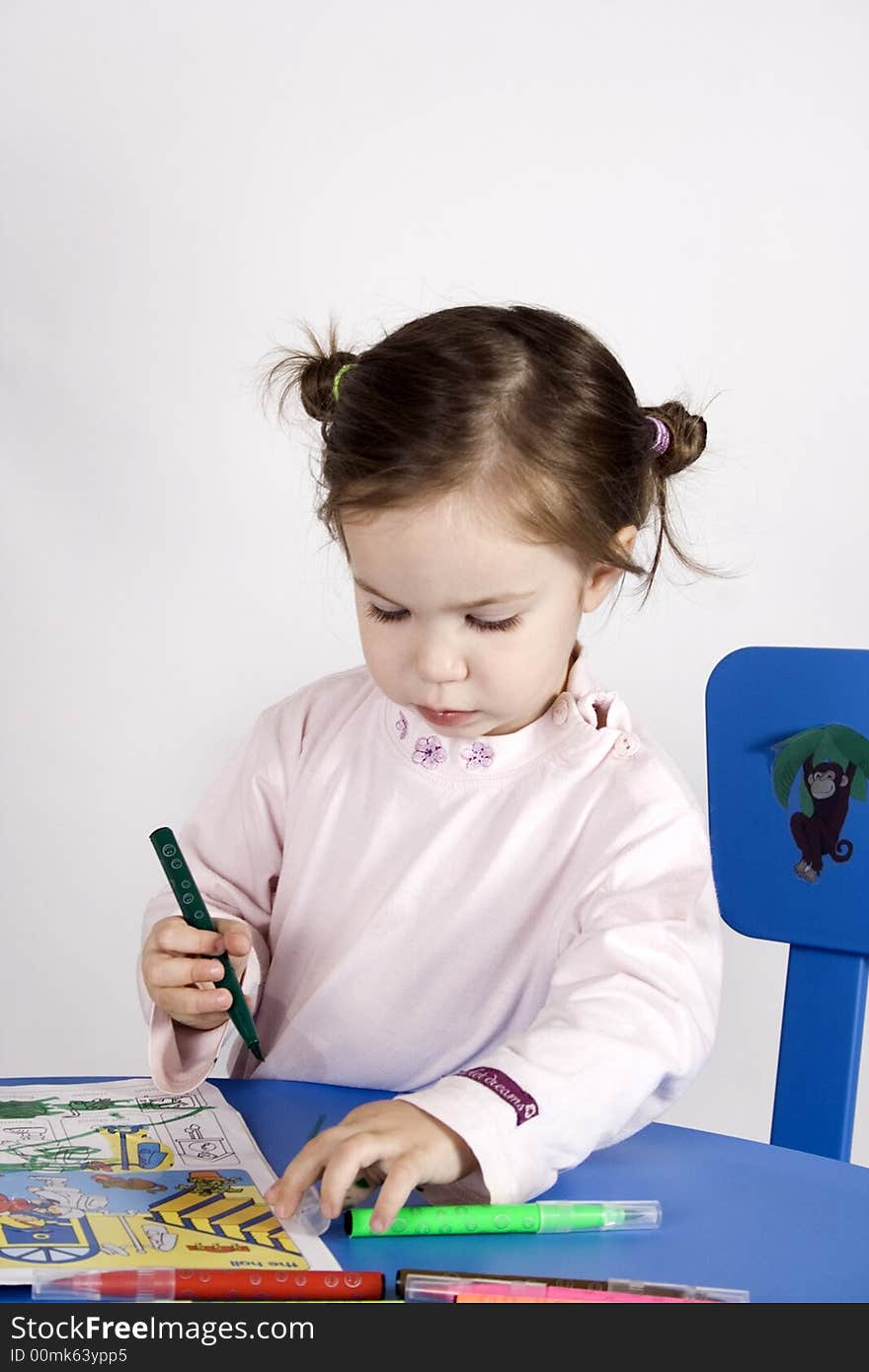 Little girl sitting on the chair and  writing on a  book