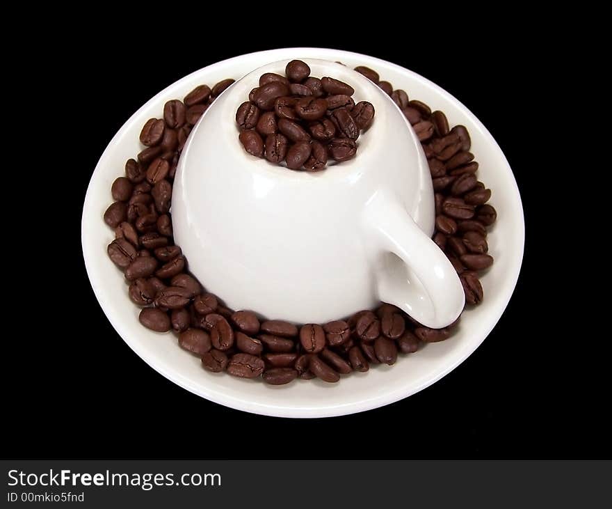 Upside down coffee mug sitting on a matching saucer with coffee beans around and on top of it.