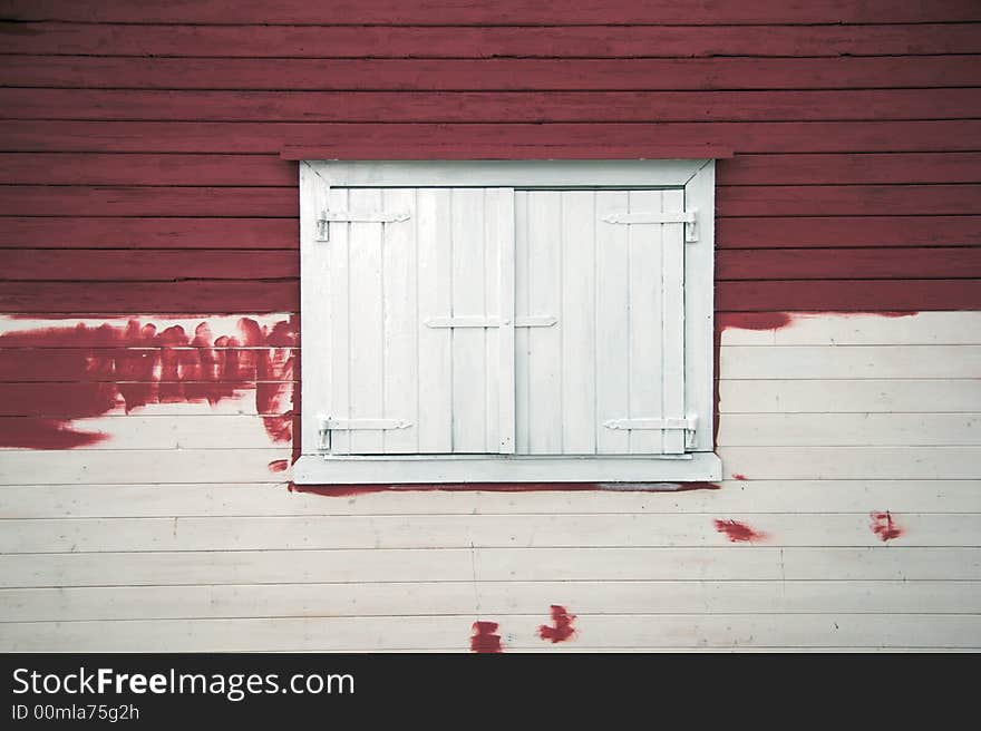 Wooden shutters on a partially painted log cabin in Norway