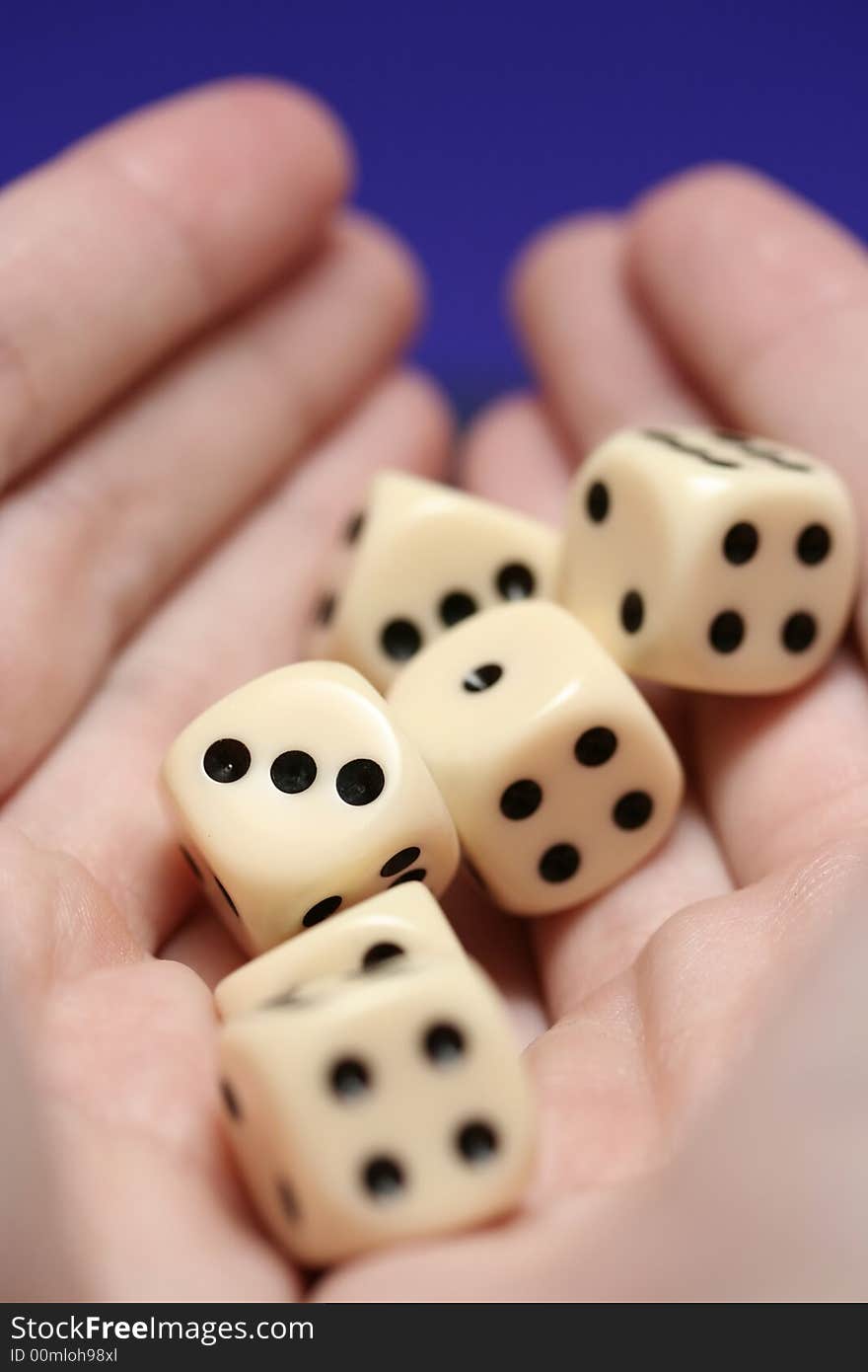 A detail of hands holding six dice. A detail of hands holding six dice.