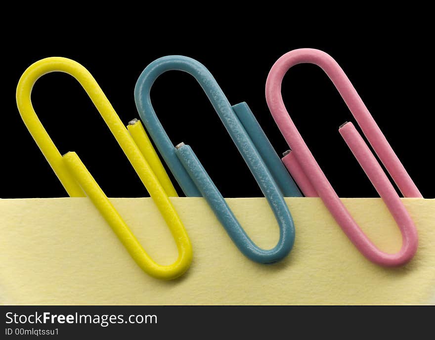 Paperclips on a yellow note with black background. Paperclips on a yellow note with black background