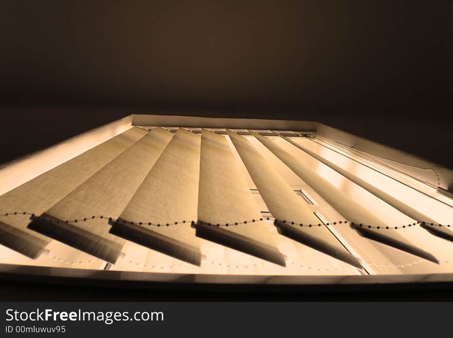 A grey window blind viewed from the bottom as the sun shines on it. A grey window blind viewed from the bottom as the sun shines on it