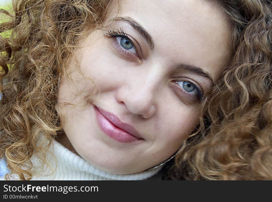 Face of smiling female with curling hair and green eyes. Face of smiling female with curling hair and green eyes