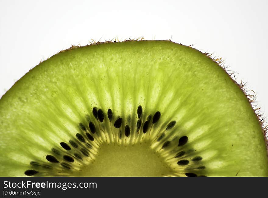 Kiwi slice, isolated and backlit with white backdrop