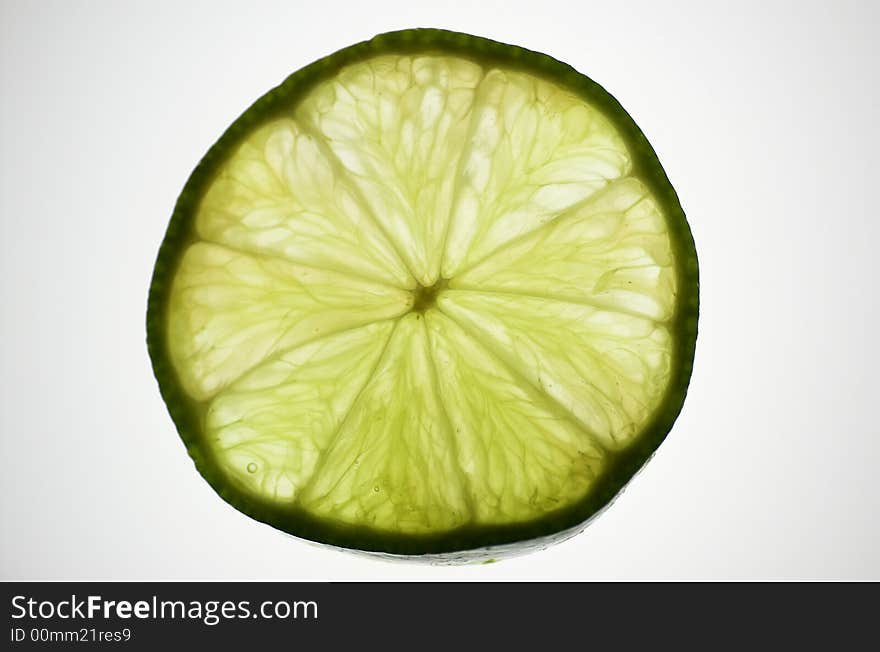 Lime slice, isolated and backlit with white backdrop