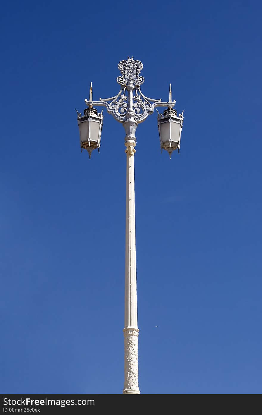 An old fashioned lamp post photographed against a bright blue sky