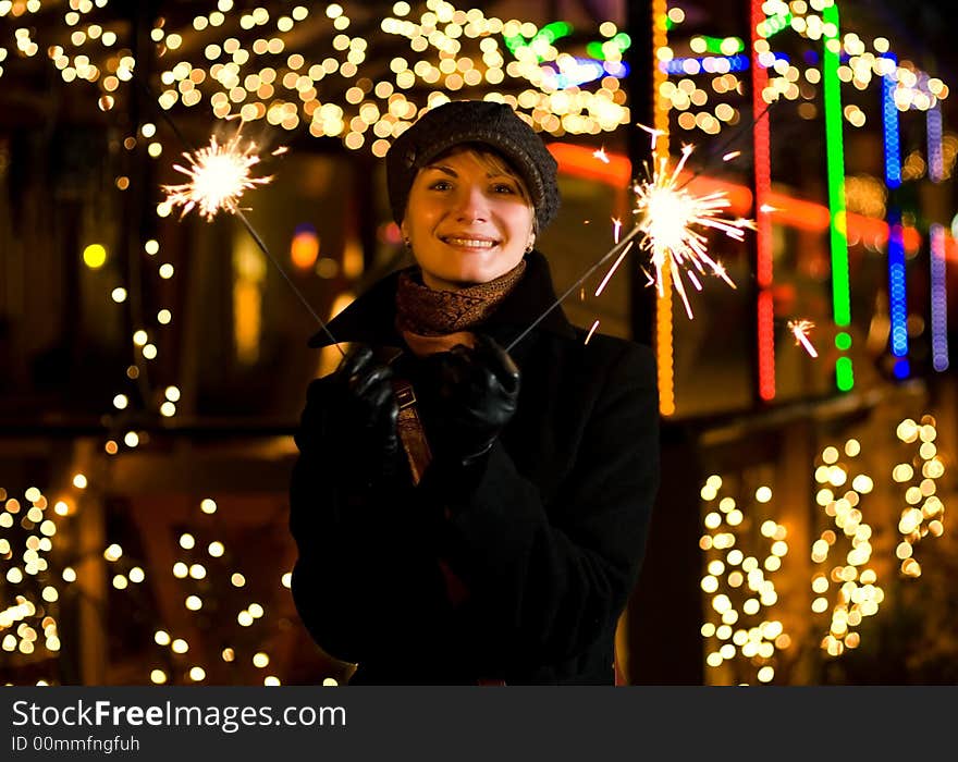 Beautiful happy girl with Christmas fireworks on abstract blurred background. Beautiful happy girl with Christmas fireworks on abstract blurred background