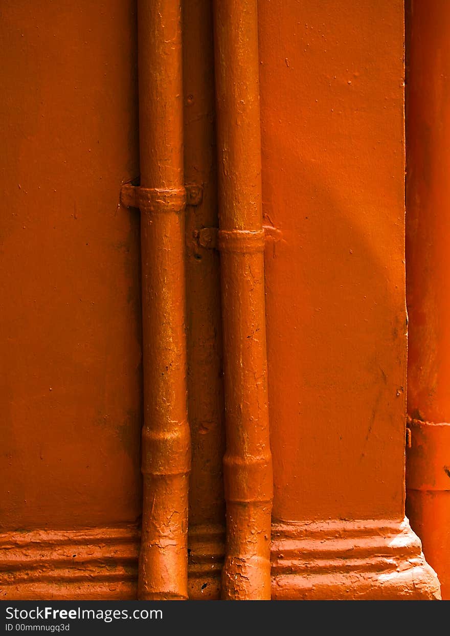 Orange Pipes running vertically up the sides of an orange coloured pillar