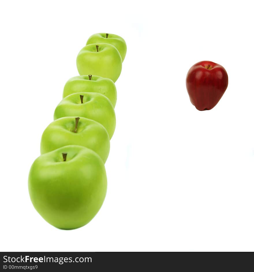 A vertical line of green apples and a red apple sit in the front of them. A vertical line of green apples and a red apple sit in the front of them