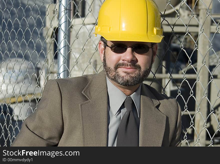 Man in suit at construction site  wearing yellow hardhat. Man in suit at construction site  wearing yellow hardhat.