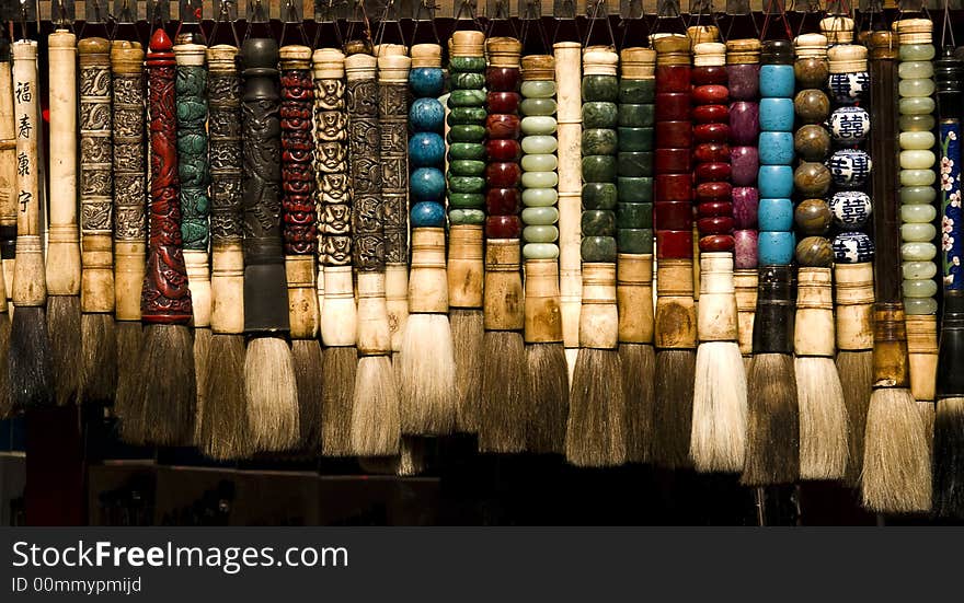 Chinese brushes in different colours hanging in a shop on a stand