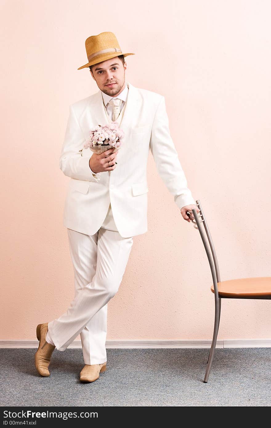 Young groom in wedding wear with bouquet of chrysanthemum. Special 	pink toned photo f/x. Young groom in wedding wear with bouquet of chrysanthemum. Special 	pink toned photo f/x