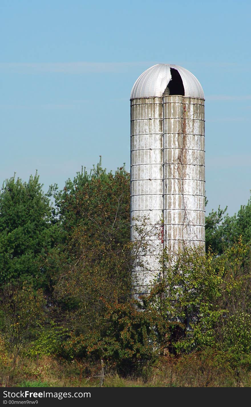 An old silo with trees against blue sky