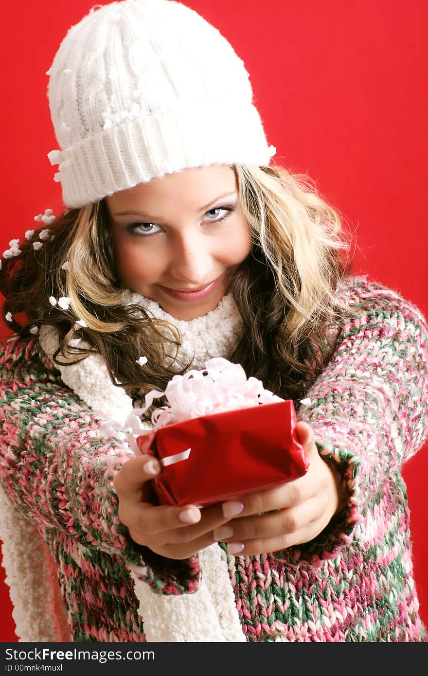 Winter portrait of a beautiful young woman with a cap  and a gift and snowblakes. Winter portrait of a beautiful young woman with a cap  and a gift and snowblakes