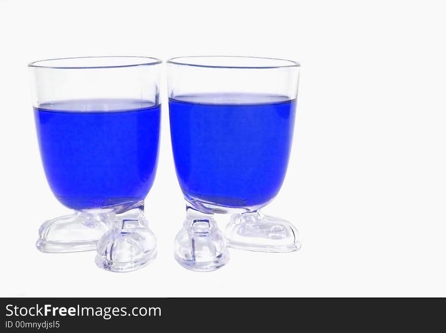 Two glass whit blue liquid one a white background. Two glass whit blue liquid one a white background