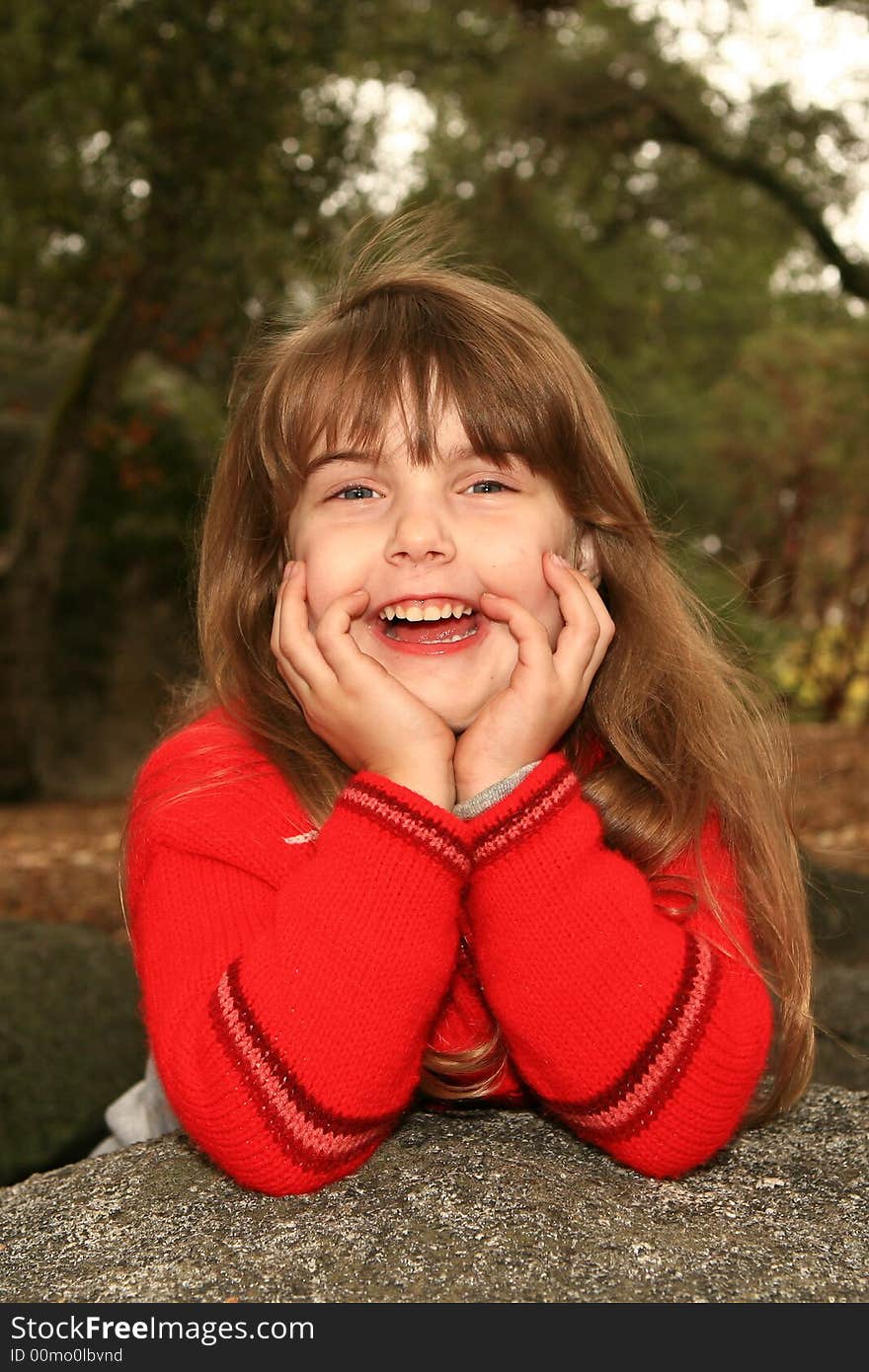 Girl Holding Her Face Smiling Outdoors on a Rock