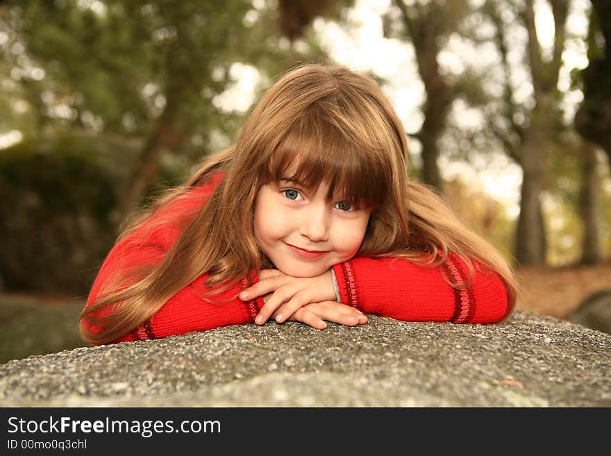 Girl Holding Her Face Smiling Outdoors on a Rock