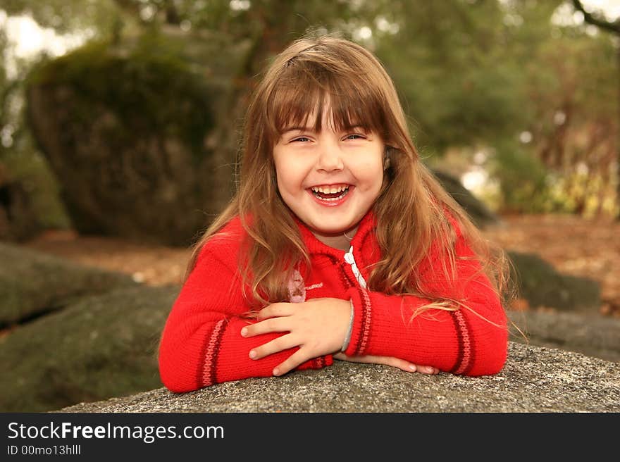 Girl Holding Her Face Smiling Outdoors on a Rock