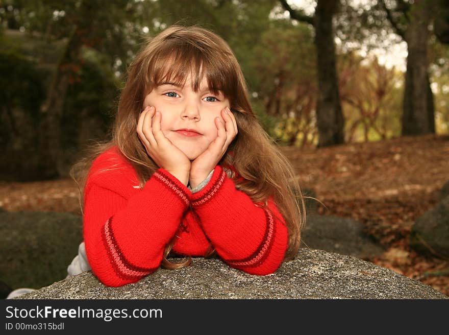 Smug Young Girl Outdoors On A Rock