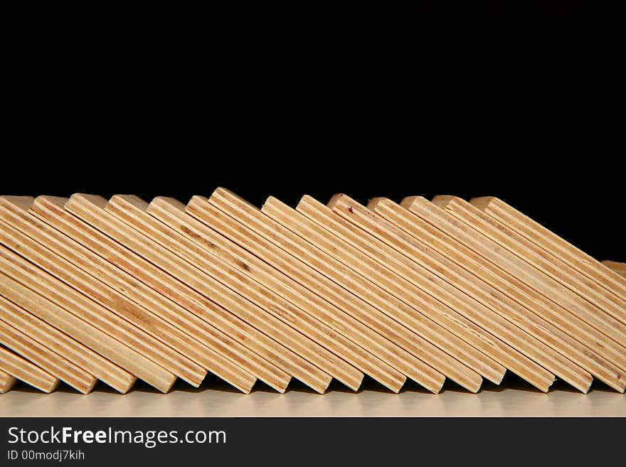 Fallen wooden domino blocks on black background.