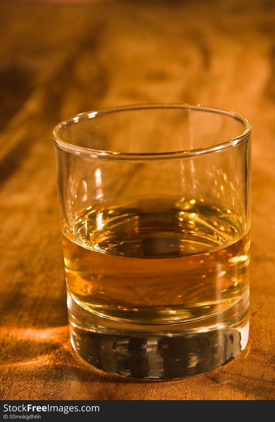 A glass of whisky in warm colored setting. A glass of whisky in warm colored setting