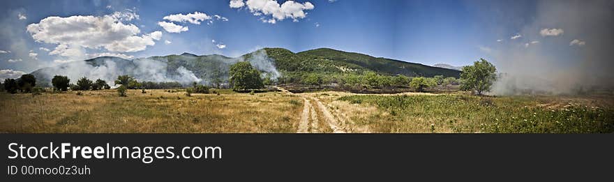 Panoramic view of a meadow with smoke from the dead fire