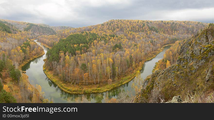 There is gray tranquil day and bright leaves. River makes a turning around hill. There is gray tranquil day and bright leaves. River makes a turning around hill.