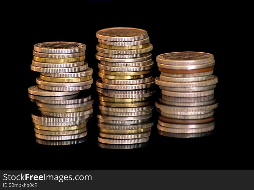 Silver and gold coins isolated on black background.