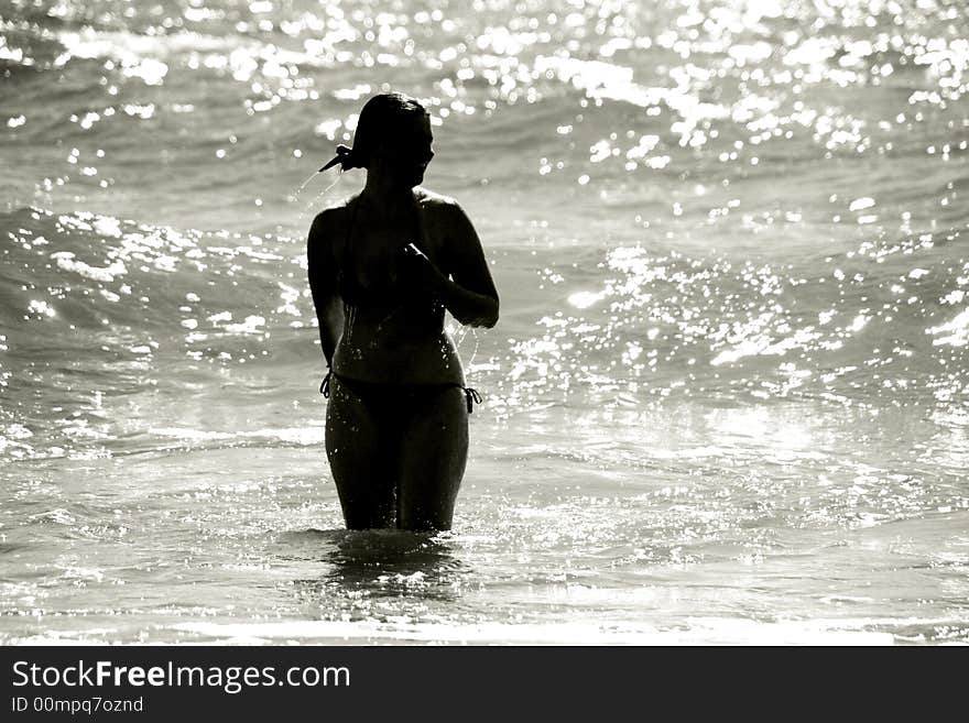 Silhouette of a wet young woman in a waving sea. Silhouette of a wet young woman in a waving sea