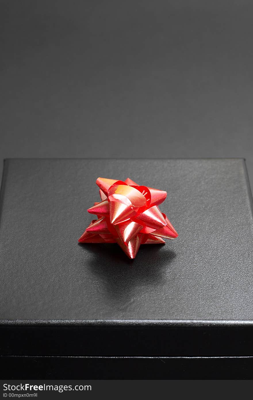 Black gift box with a red bow on black background. Black gift box with a red bow on black background