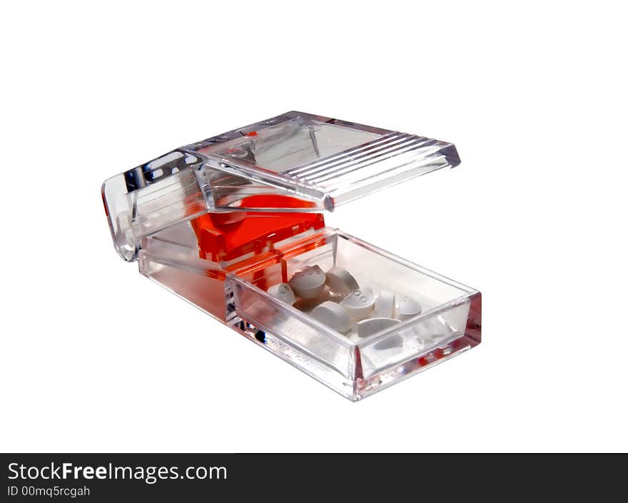 A clear pill cutter / splitter with pills and tablets.