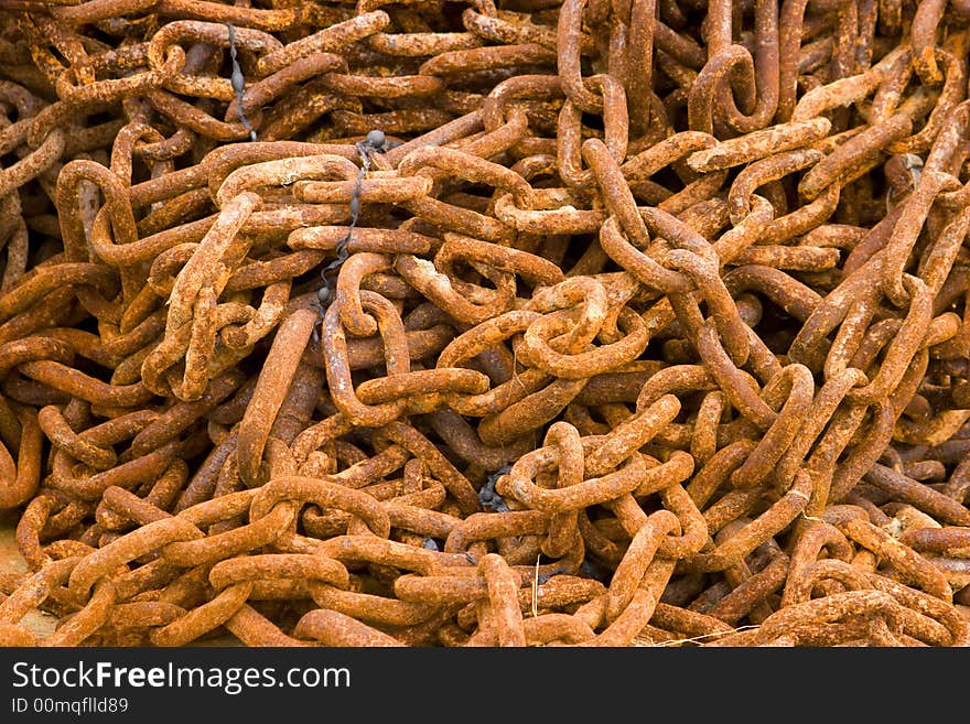 A pile of rusty chains encrusted with salt lying on the beach