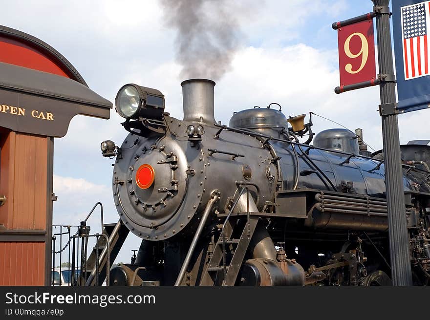 A partial view of a large, authentic steam locomotive and engine, including the coal burning boiler as it waits at a train stations for passengers to board. A partial view of a large, authentic steam locomotive and engine, including the coal burning boiler as it waits at a train stations for passengers to board.