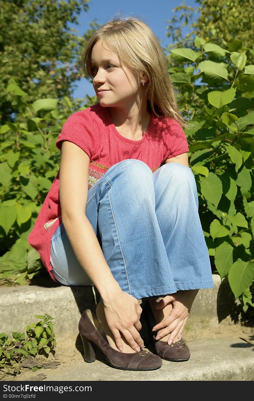 Blond smiling girl sitting on footsteps