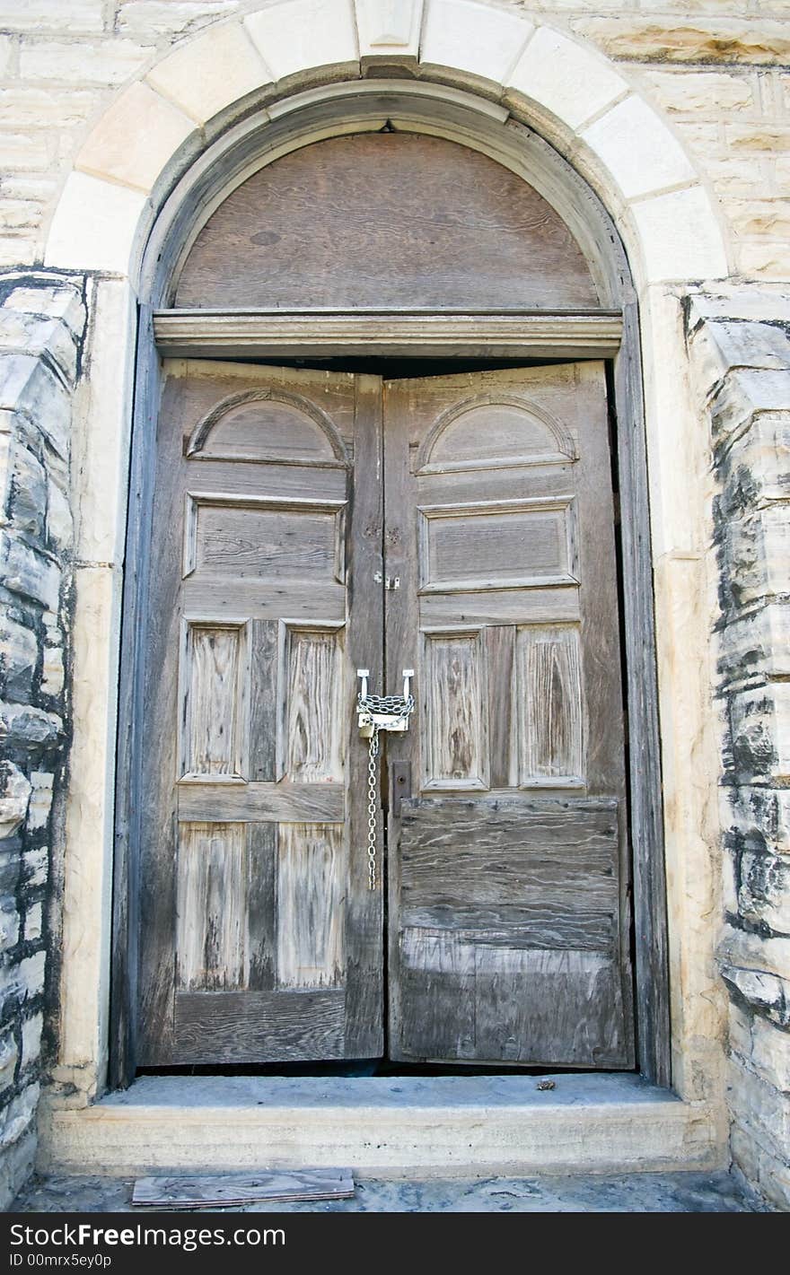 An old weathered door of a church building chained and padlocked shut. An old weathered door of a church building chained and padlocked shut.