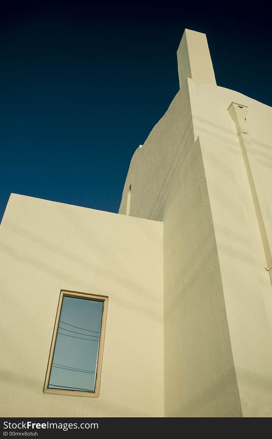 The sharp angles and lines of an adobe white building contrasted against the deep sky above. The sharp angles and lines of an adobe white building contrasted against the deep sky above.