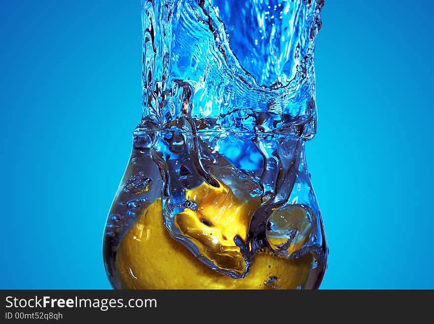 Close-up of splash of blue fluid in a glass with lemon