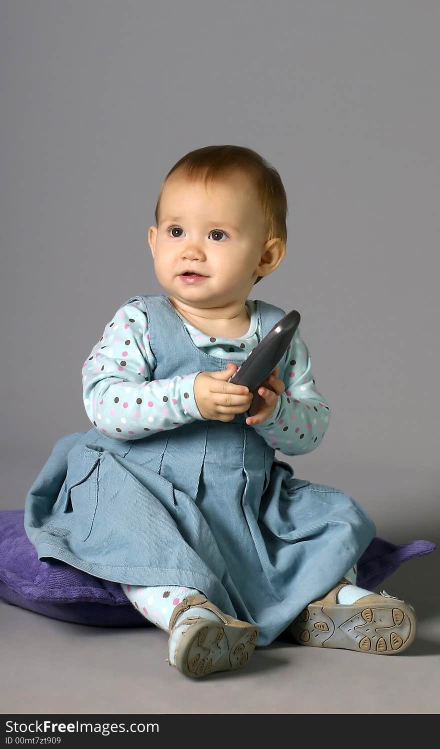 The child calling by phone on a grey background with a smile