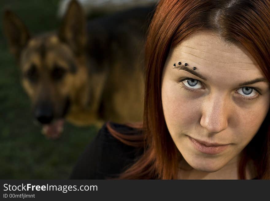 A girl seductively staring at the camera with her dog (german shepherd) in the background. A girl seductively staring at the camera with her dog (german shepherd) in the background.