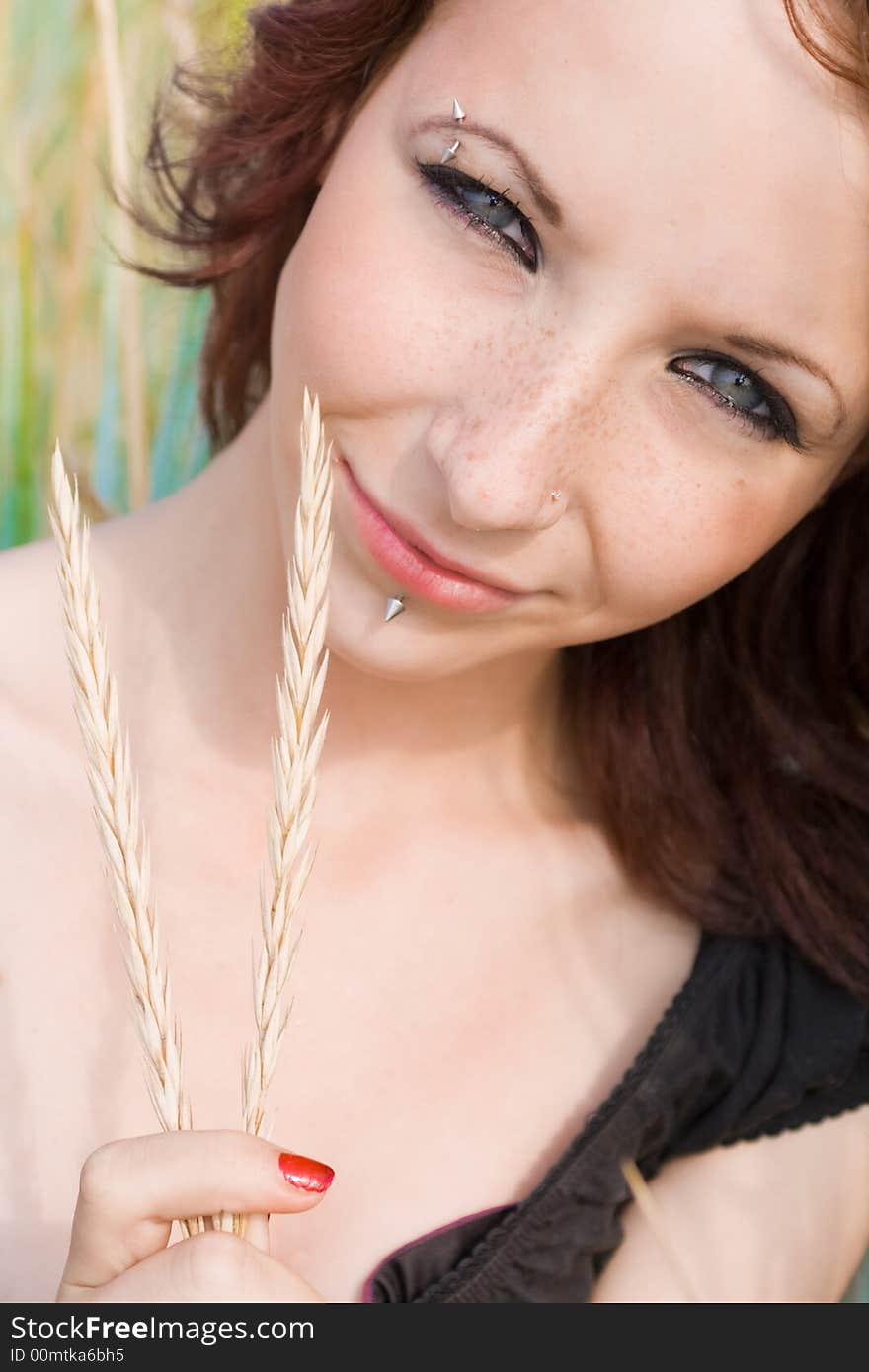 Pretty young girl smiling and holding wheat in her hand. Pretty young girl smiling and holding wheat in her hand