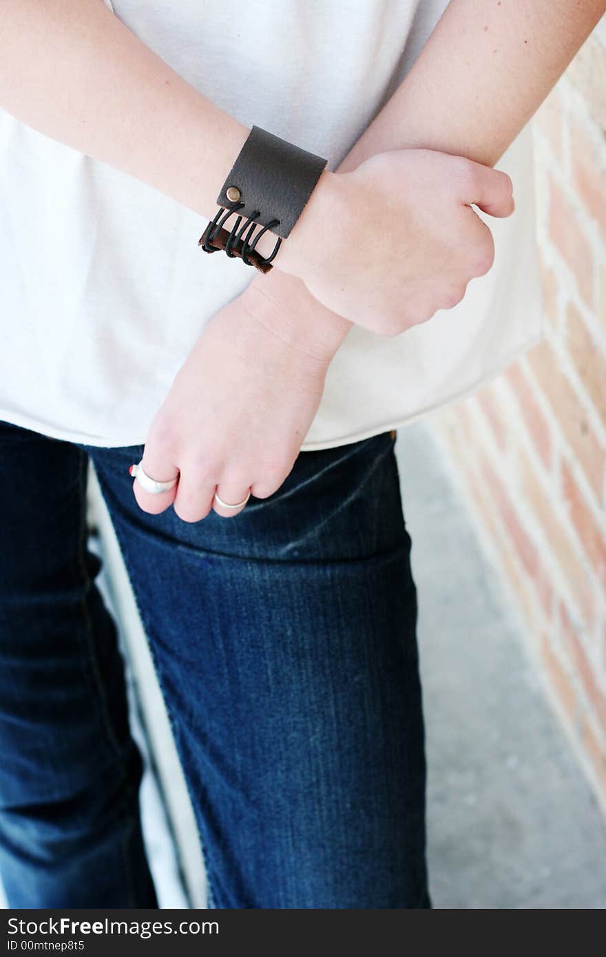 Close-up view of female's midsection with one hand holding other arm, casual clothing. Close-up view of female's midsection with one hand holding other arm, casual clothing