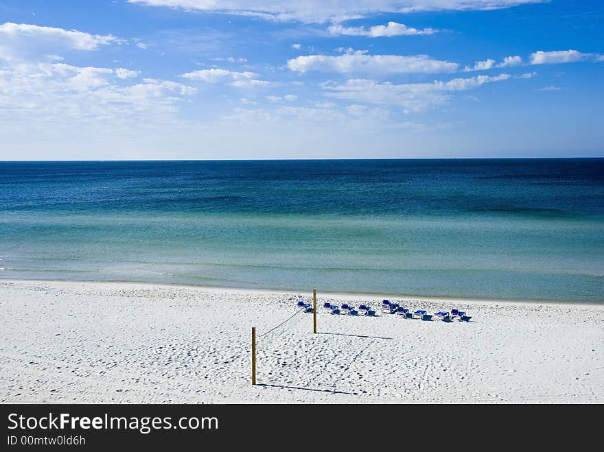 Picture of a volleyball net and benches on a beach facing the sea signifying fun and relaxation. Picture of a volleyball net and benches on a beach facing the sea signifying fun and relaxation